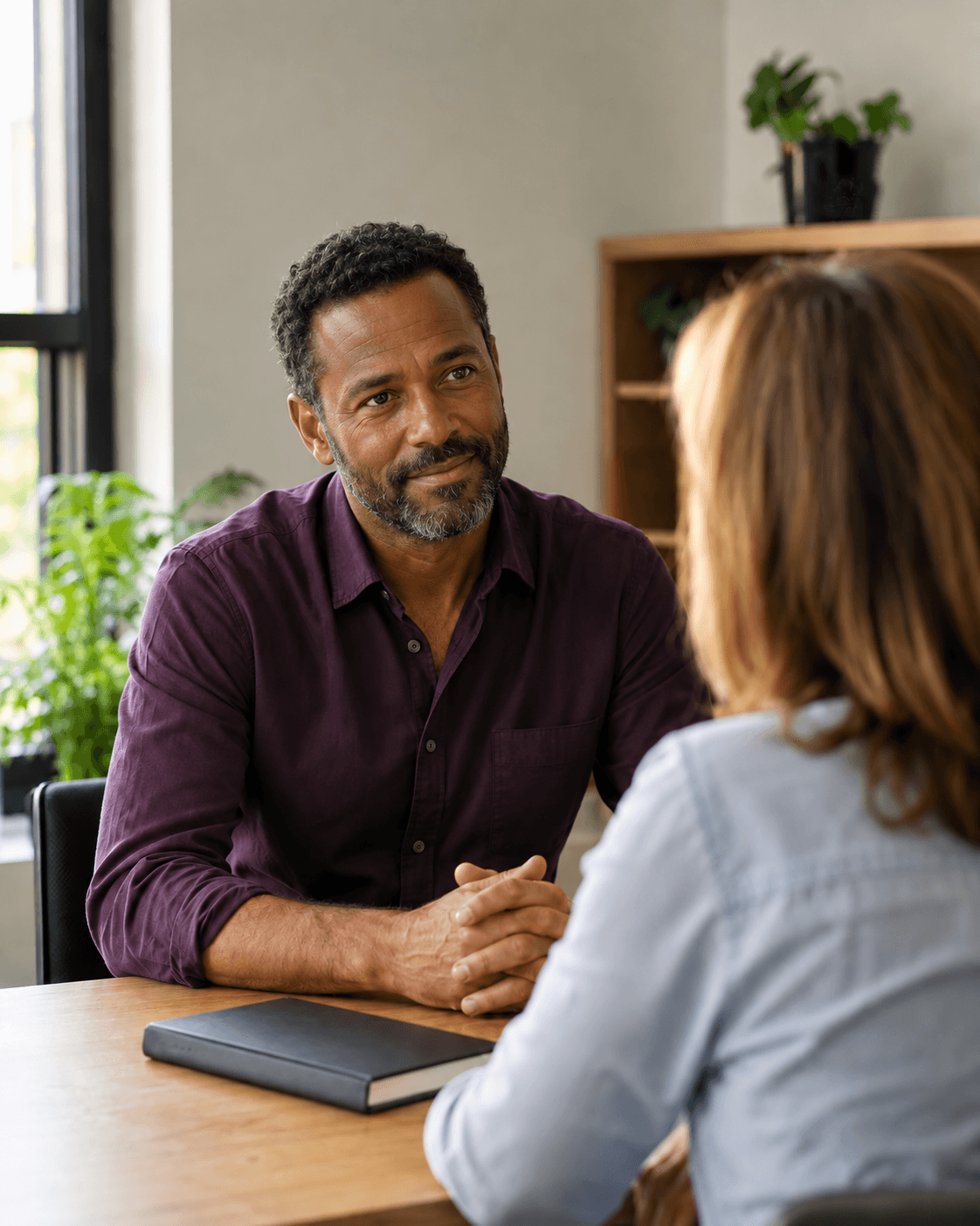 An African-American business coach in purple listening during a one-to-one conversation